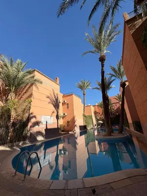 a swimming pool with palm trees next to a building at Riad Miralezia in Marrakech