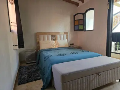 a bedroom with a bed with a blue blanket and a window at Riad Miralezia in Marrakech