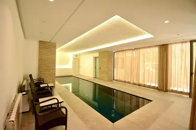 a swimming pool in a room with two chairs at Villa MAÙRA Marrakech in Marrakech