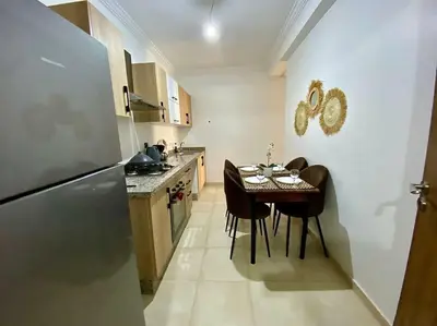 a small kitchen with a table and a refrigerator at apparte 2 chambres de luxe en face la gare gueliz in Marrakech