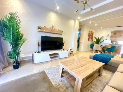 a living room with a large television and a table at Les Douces Nuits De Marrakech in Marrakech