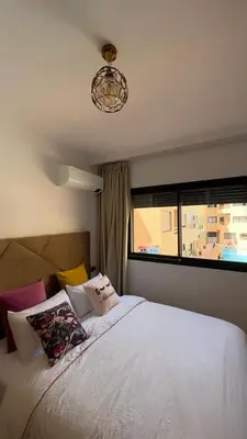 a bedroom with a white bed with a window at Appartement de lux in Marrakech