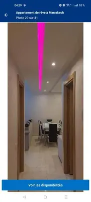 a room with a table and a pink light on the ceiling at Charming Apartment in the Heart of Marrakech - Modern Amenities and Prime Location in Marrakech