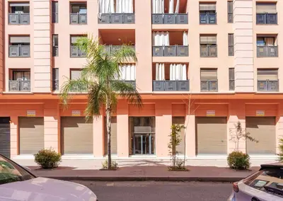 an apartment building with closed garage doors and palm trees at Menara garden in Marrakech