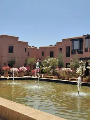 a fountain in a pond in a courtyard with buildings at les jardins d'atlas waky palm golf in Marrakech