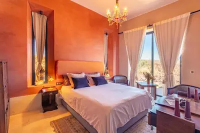 a bedroom with a large bed and a chandelier at Villa Kela Serene in Marrakech
