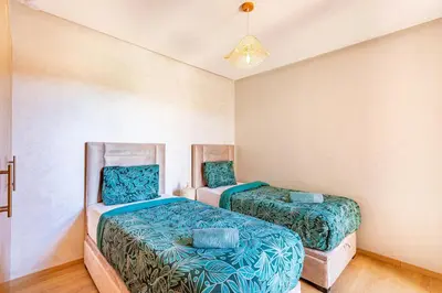 a bedroom with two beds and a chandelier at Résidence Golfique ,Piscine,Jardin terrasse privée in Marrakech