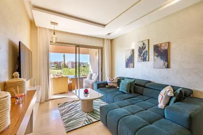 a living room with a blue couch and a table at Résidence Golfique ,Piscine,Jardin terrasse privée in Marrakech