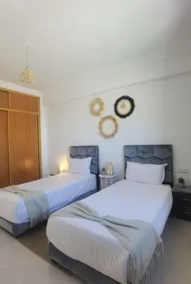 two beds in a room with white walls at Family House Marrakech in Marrakech
