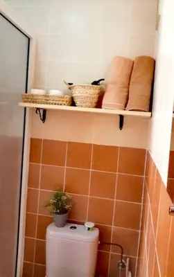 a bathroom with a toilet with towels and a shelf at Family House Marrakech in Marrakech
