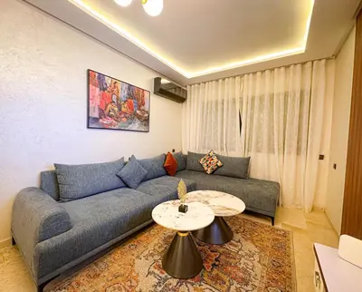 a living room with a blue couch and a table at Bel appartement haut standing in Marrakech