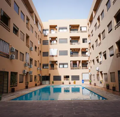 an apartment building with a swimming pool in the courtyard at Bel appartement haut standing in Marrakech