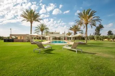 a yard with two chairs and a house with palm trees at Villa des stars in Marrakech