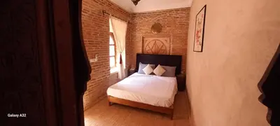 a bedroom with a bed and a brick wall at Riad maison Bounouar in Marrakech