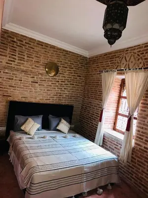 a bedroom with a large bed in a brick wall at Riad maison Bounouar in Marrakech