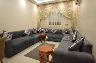a living room with a blue couch and a table at Appartement familial proche aéroport et Oasiria in Marrakech