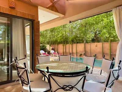 a patio with a table and chairs and a pool at Villa Oasis in Marrakech
