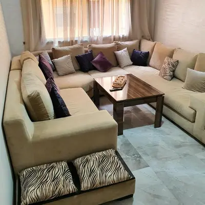 a living room with a couch and a table at Appartement près du hôtel IBIS et WAZO et Marjane Mall in Marrakech