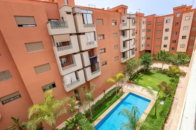 an apartment building with a swimming pool in front of it at New! App Émeraude Confort avec piscine & parking in Marrakech