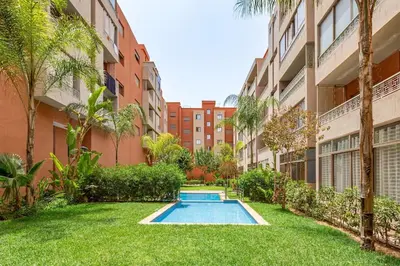 an apartment yard with a swimming pool in a building at New! App Émeraude Confort avec piscine & parking in Marrakech