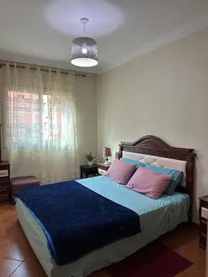 a bedroom with a bed with blue and pink pillows at Appartement Marrakech Avec Piscine in Marrakech