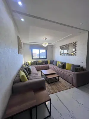 a living room with a couch and a table at Le Paradis Balnéaire - 2 min Plage - 2 chambres in Marrakech