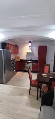 a kitchen with a refrigerator and a table and chairs at Résidence hamza appartement 2 chambre in Marrakech