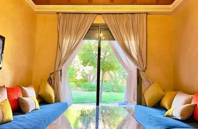 a living room with a blue couch and a large window at Palmeraie vue piscine 3 in Marrakech