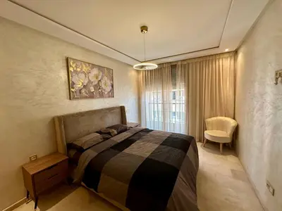 a bedroom with a bed and a chair in it at Appartement 2 chambres salon à coté de carré éden 10 in Marrakech