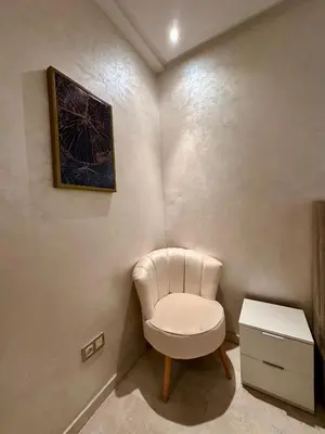 a white chair sitting in a corner of a room at Appartement 2 chambres salon à coté de carré éden 10 in Marrakech