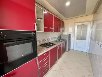 a kitchen with red cabinets and a stove top oven at Appartement 2 chambres salon à coté de la gare centre de guéliz 21 in Marrakech