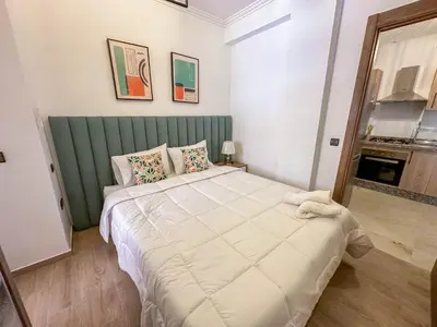 a bedroom with a large bed with a green headboard at Charmant appartement in Marrakech