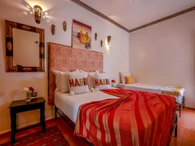 a bedroom with two beds and a mirror at Riad Nakhla in Marrakech