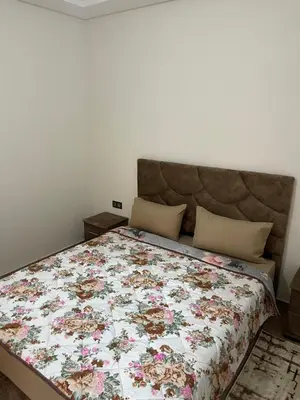 a bedroom with a bed with a floral bedspread at Appartement à louer Marrakech in Marrakech