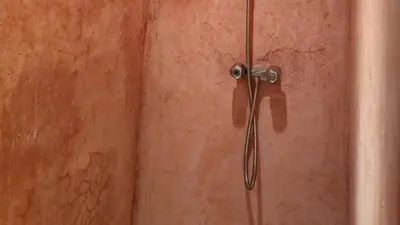 a shower door with a shower head on a wall at Riad Sleeps 2 with Rooftop Views in Marrakech