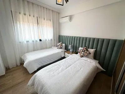 a bedroom with two beds and a green headboard at Grand appartement moderne in Marrakech