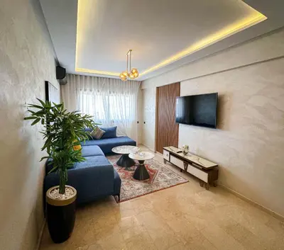 a living room with a blue couch and a tv at Grand appartement moderne in Marrakech