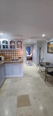 a kitchen with white cabinets and a table in a room at Résidence Nadia 3 étage appartement 22 in Marrakech