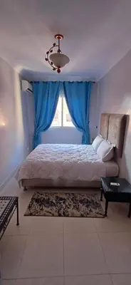 a bedroom with a bed with a blue curtain and a window at Résidence Nadia 3 étage appartement 22 in Marrakech