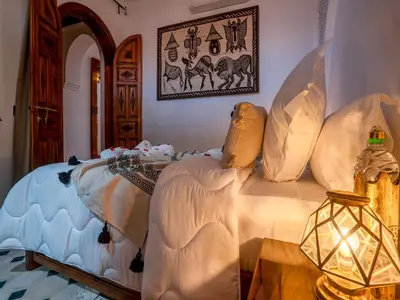a bedroom with a bed with pillows and a lamp at Belle Riad de médina in Marrakech