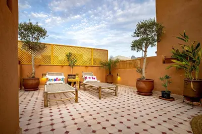 a patio with two chairs and a table and trees at Riad Brothers in Marrakech