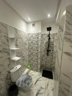 a bathroom with a white toilet and marble walls at Centre ville T3 jacuzzi privé 2 min de la gare in Marrakech