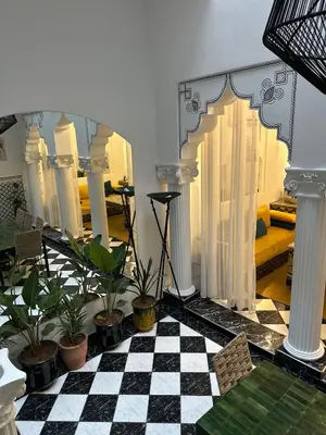 a room with a checkered floor with plants and columns at Riad Nolya Luxury Marrakech - Totalement Rénové - Capacité jusqu à 10 lits spacieux in Marrakech
