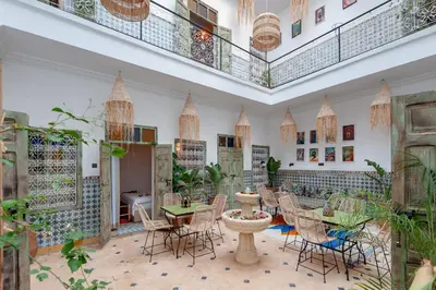 a restaurant with tables and chairs in a room with plants at Riad Bab Taghzout Marrakech in Marrakech