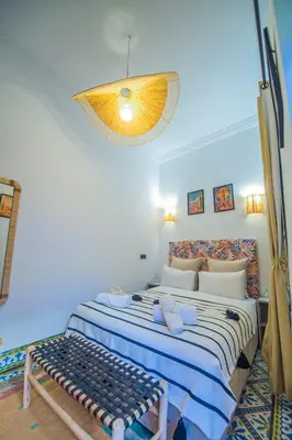 a bedroom with a bed with a bench in it at Riad Bab Taghzout Marrakech in Marrakech