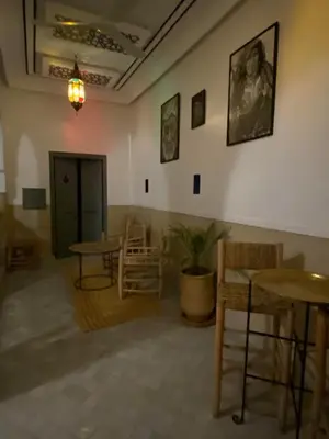 a room with tables and chairs and a painting on the wall at Riad DAR OMI ZAHRA in Marrakech