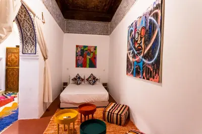 a bedroom with a bed and two chairs and a painting at Riad Sala Art Marrakech in Marrakech