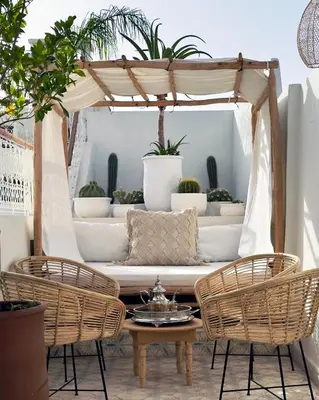 a patio with rattan furniture and potted plants at Riad Jalma in Marrakech