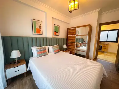 a bedroom with a large white bed and a mirror at Prestigieux Appartement in Marrakech