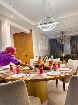 a woman sitting at a table in a living room at villa argan golf piscine chauffée in Marrakech
